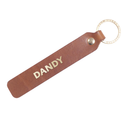 Flatlay, Schlüsselanhänger aus Leder in Natur mit Goldprägung 'Dandy' von LoveTag, handgefertigt in Wien