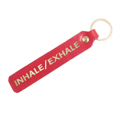 Flatlay, Schlüsselanhänger aus Leder in Rot mit Goldprägung 'Inhale Exhale' von LoveTag, handgefertigt in Wien
