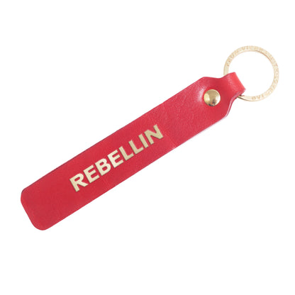 Flatlay, Schlüsselanhänger aus Leder in Rot mit Goldprägung 'Rebellin' von LoveTag, handgefertigt in Wien