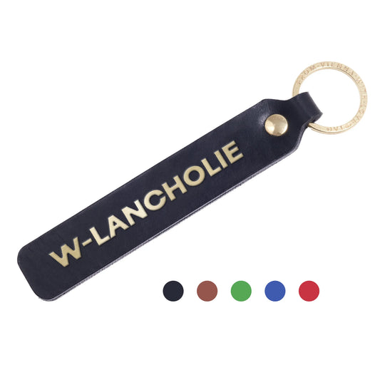 Flatlay, Schlüsselanhänger aus Leder in Schwarz mit Goldprägung 'W-Lancholie' von LoveTag, handgefertigt in Wien