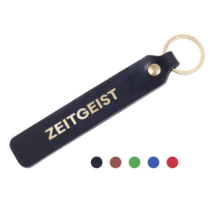 Flatlay, Schlüsselanhänger aus Leder in Schwarz mit Goldprägung 'Zeitgeist' von LoveTag, handgefertigt in Wien